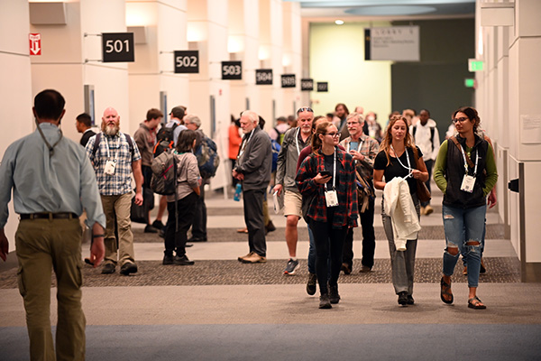 Conference attendees walk in a busy hall.