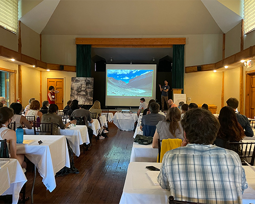 People listen to a presentation in a lodge-like setting.