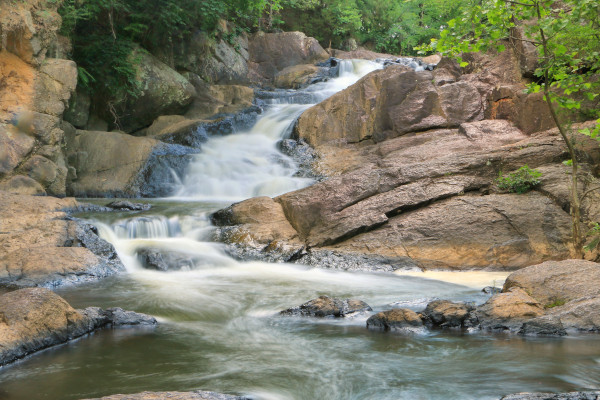 A large creek flows over a smooth, rocky formation.