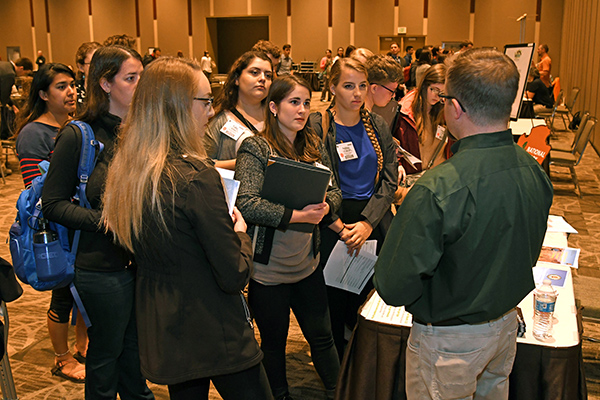 A small group of young people converse with a speaker.