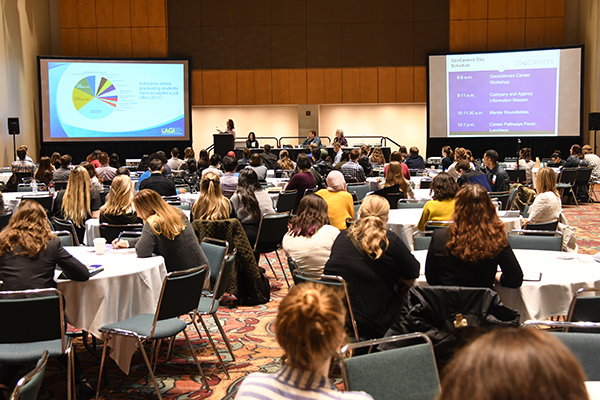 Tables of young people listen to a presentation.