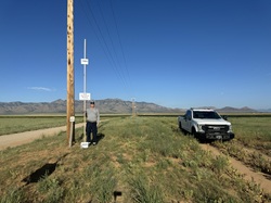 Person holding sign standing next to electrical pole.