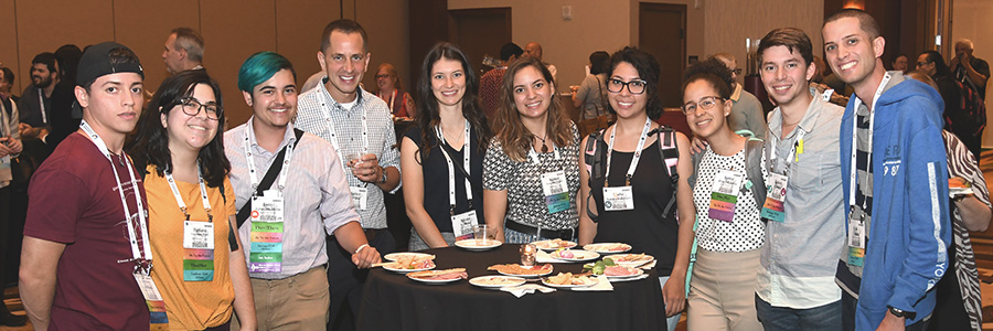 A group of OTF students stand near a table and smile at the camera.