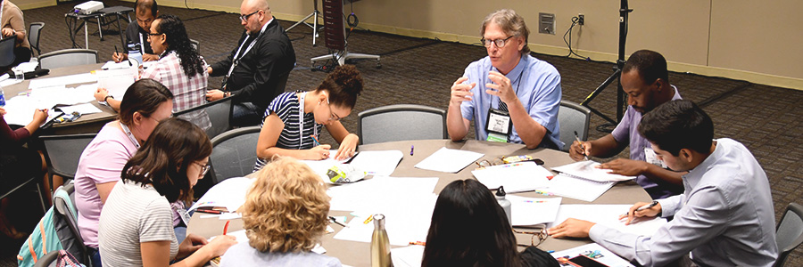 A group sits at a round table listening to one member speak at GSA Annual Meeting.