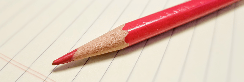 Red editing pencil on legal pad.
